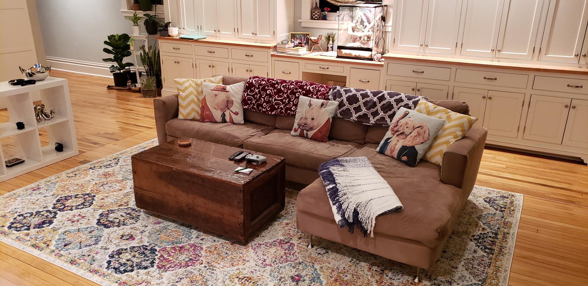 Safavieh Madison Collection area rug in a living room with sectional sofa, showcasing a distressed medallion pattern in cream and multicolor tones