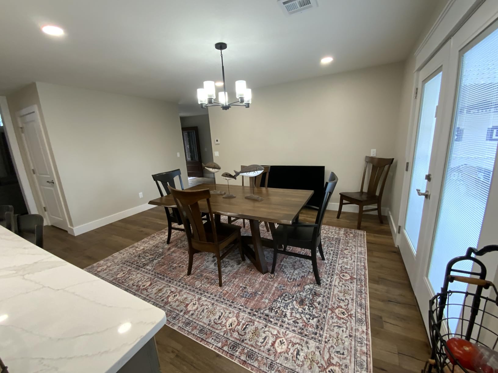 Traditional distressed Oriental rug in red and cream tones placed under a wooden dining table with four chairs in a modern dining room